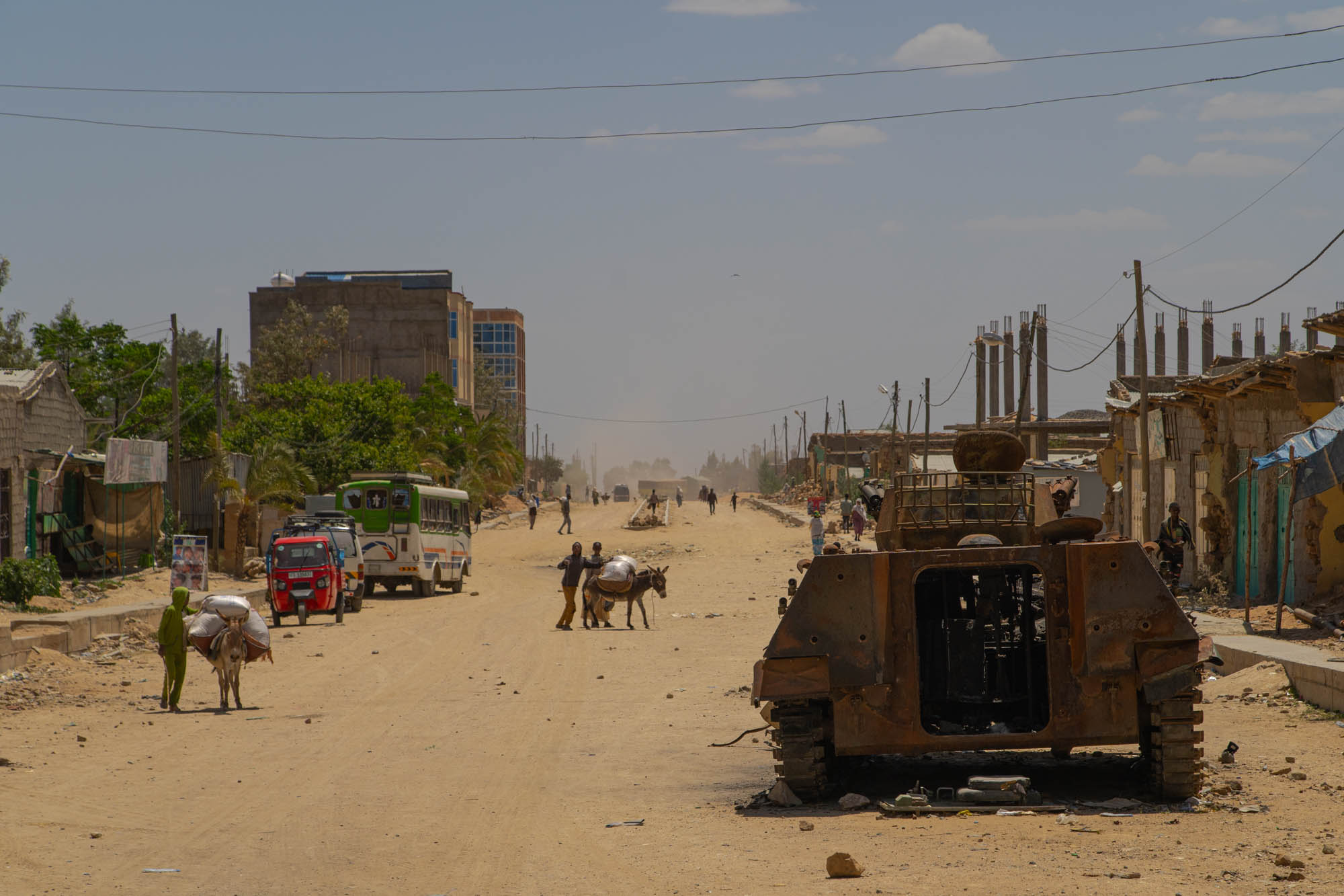 Civilians pass a destroyed armoured vehicle on a street in Hawzen, Tigray